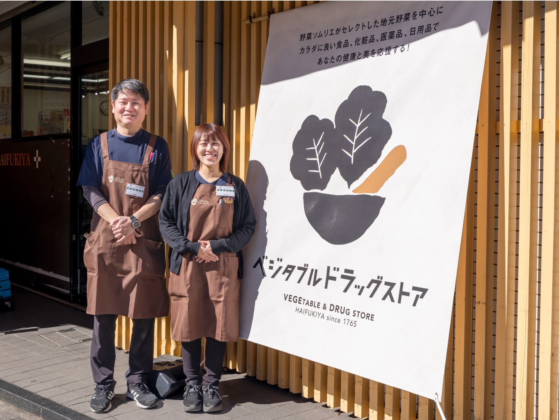 ベジタブルドラッグストアの前で並ぶスタッフと店舗ロゴ